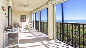 Uma varanda com vista para o oceano, um ventilador de teto e algumas cadeiras.