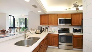 Uma cozinha moderna com armários de madeira, eletrodomésticos de aço inoxidável e uma grande janela que traz luz natural.