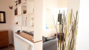 A living room with a sofa, a radiator, a wooden table, and a bookshelf. - Spanish steps luxury loft apartment (Roma)