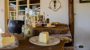 A rustic kitchen with a wooden table displaying various cheeses and bottles. - Pousada Vale das Primaveras (Tres Coracoes)