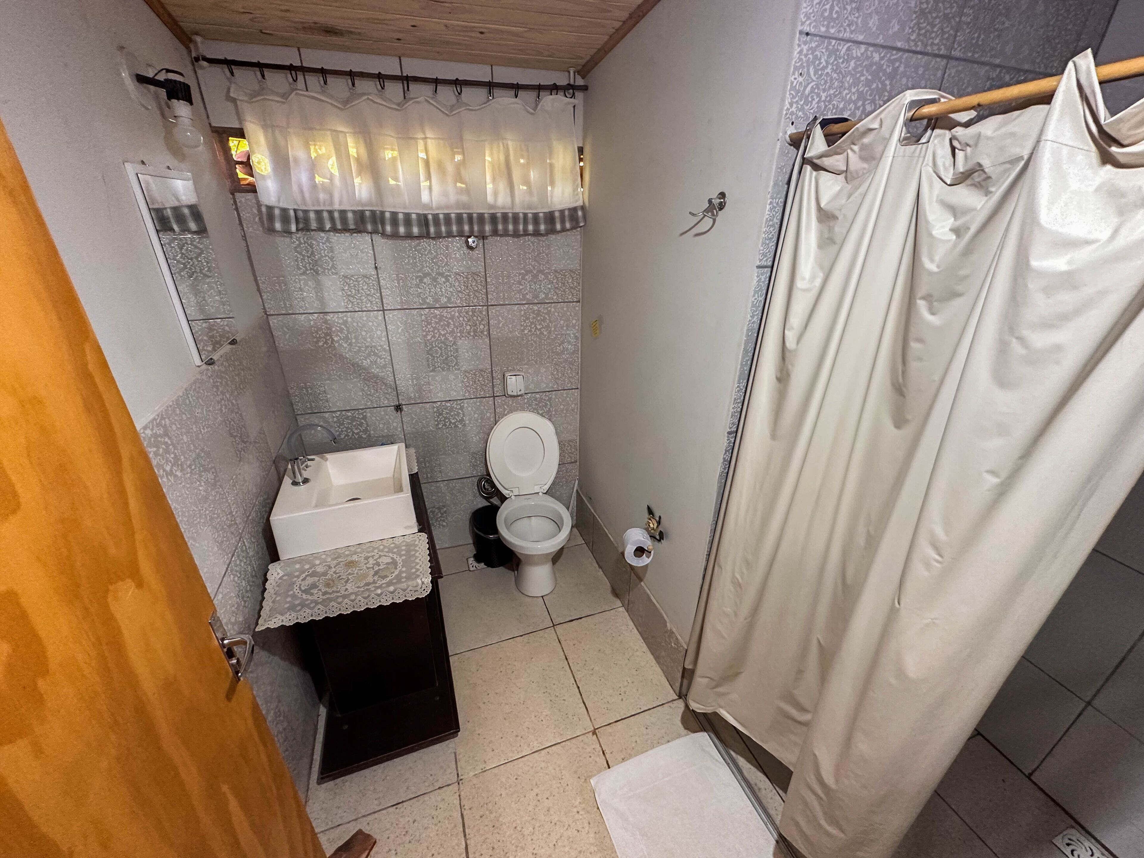 A small bathroom with a toilet, sink, and shower curtain.