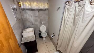 A small bathroom with a toilet, sink, and shower curtain.