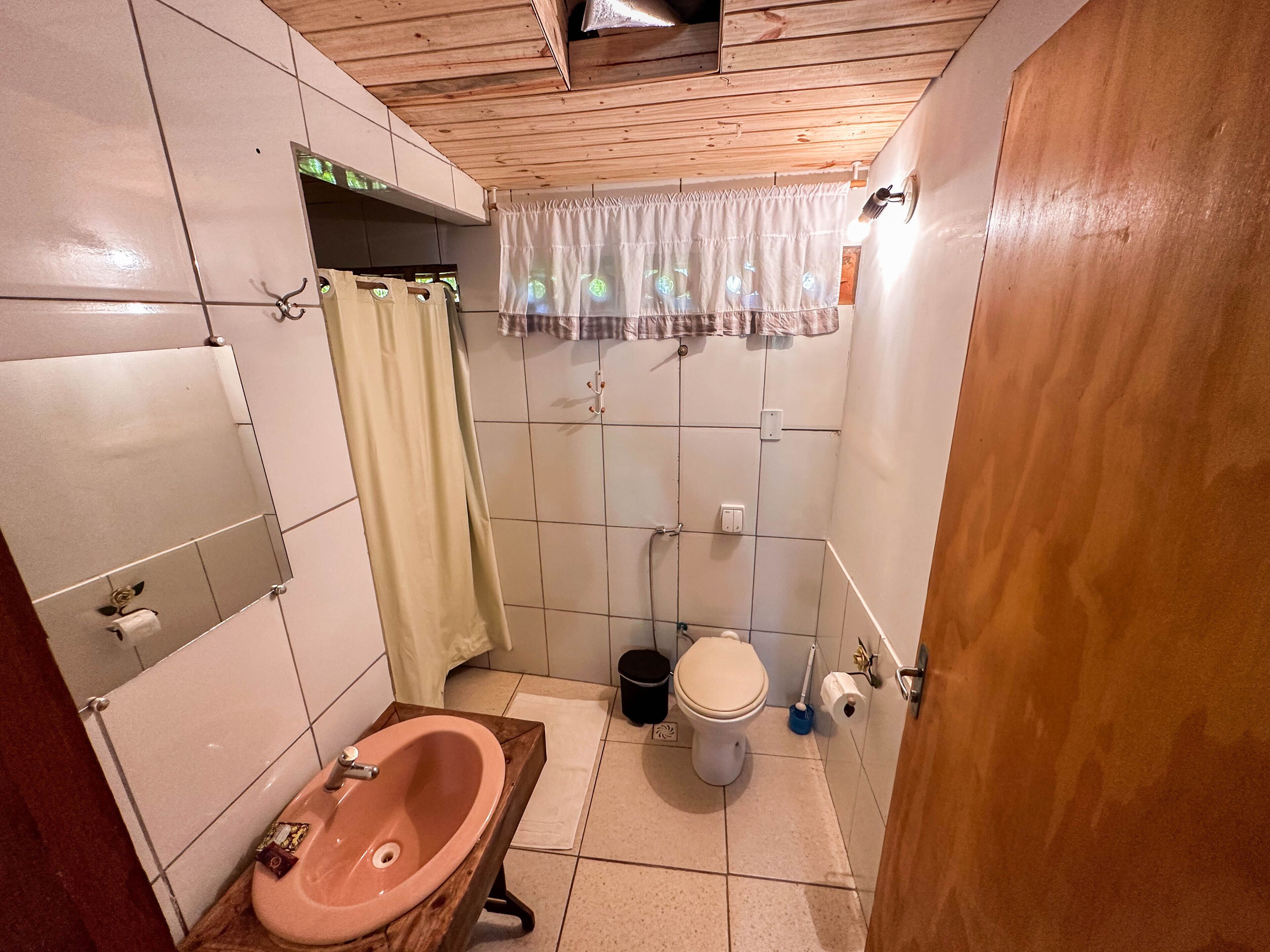 A small bathroom with a wooden bathtub, a toilet, and a sink.