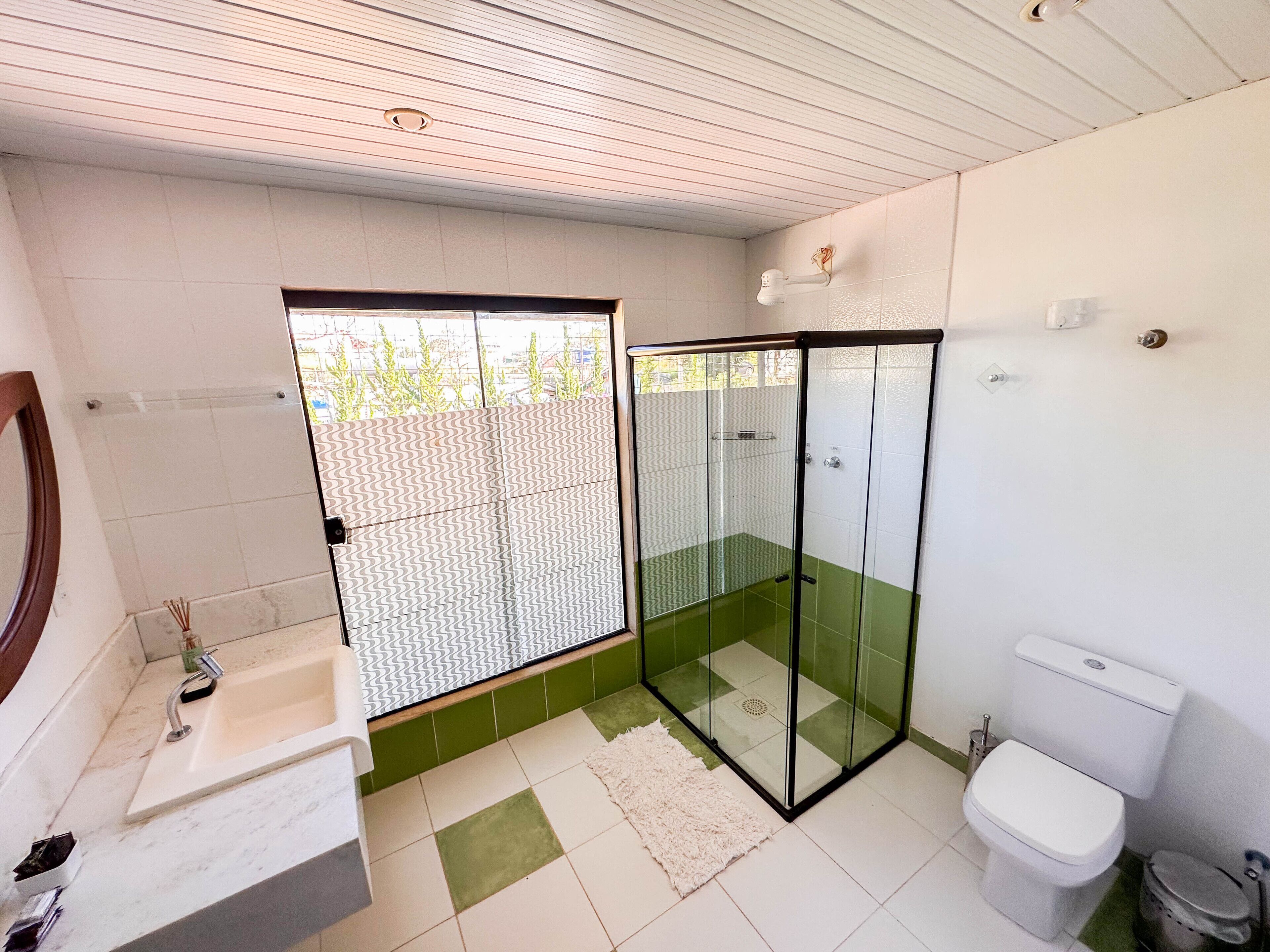 A modern bathroom with a glass shower enclosure, a white toilet, and a sink with a mirror.