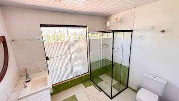 A modern bathroom with a glass shower enclosure, a white toilet, and a sink with a mirror.