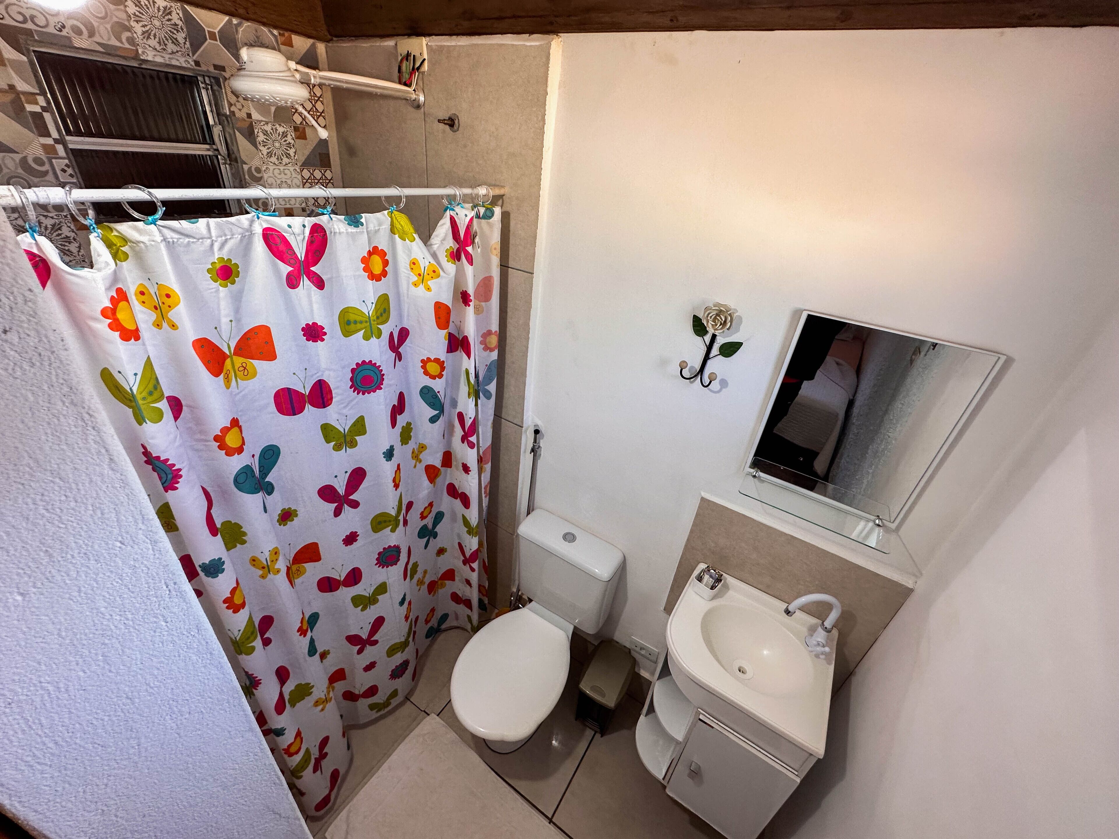 Un baño con inodoro, lavamanos y cortina de ducha con motivos de mariposas.