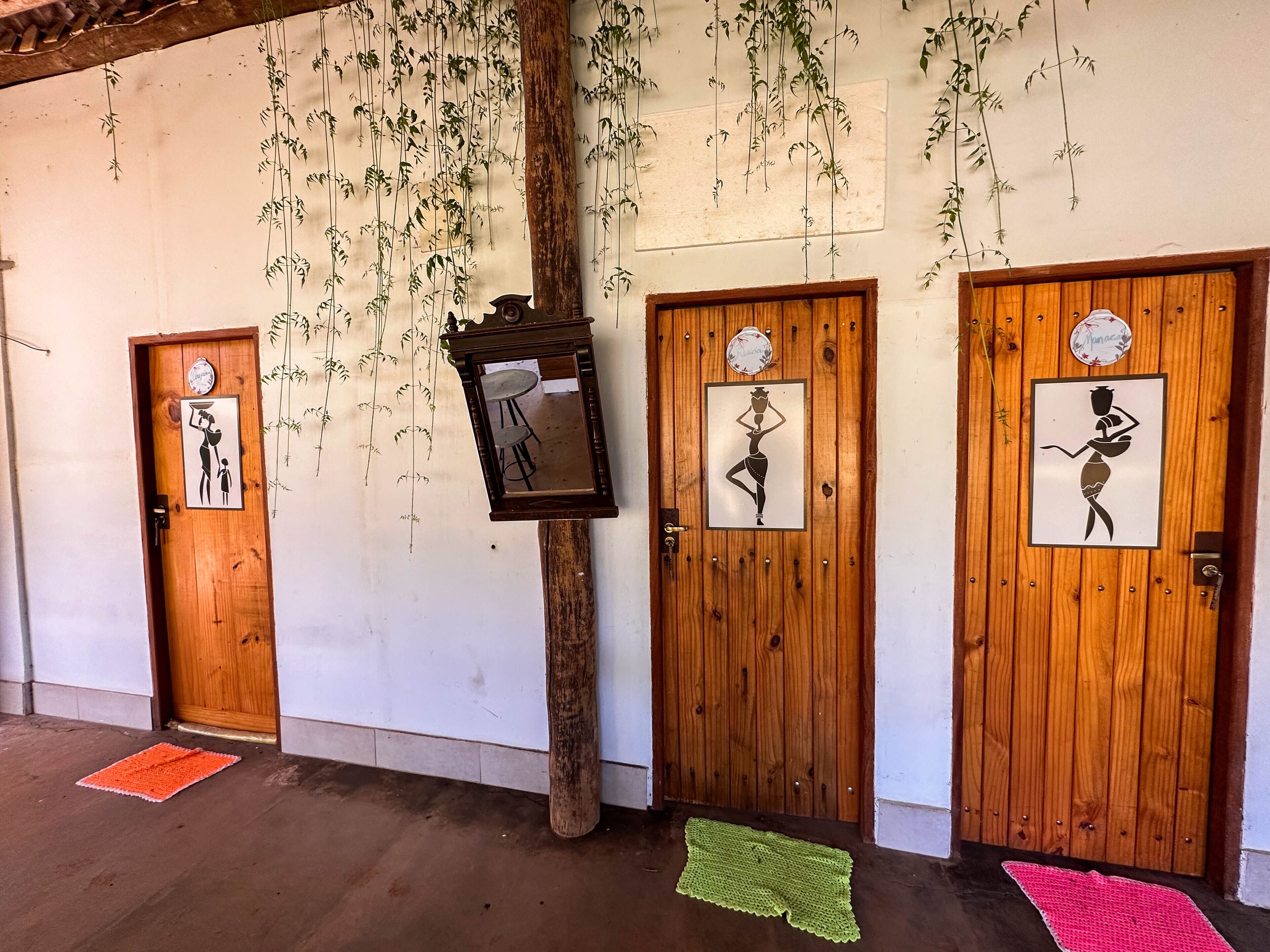 Un couloir avec des portes en bois, chacune ornée d’une œuvre d’art unique et agrémentée d’un petit tabouret.