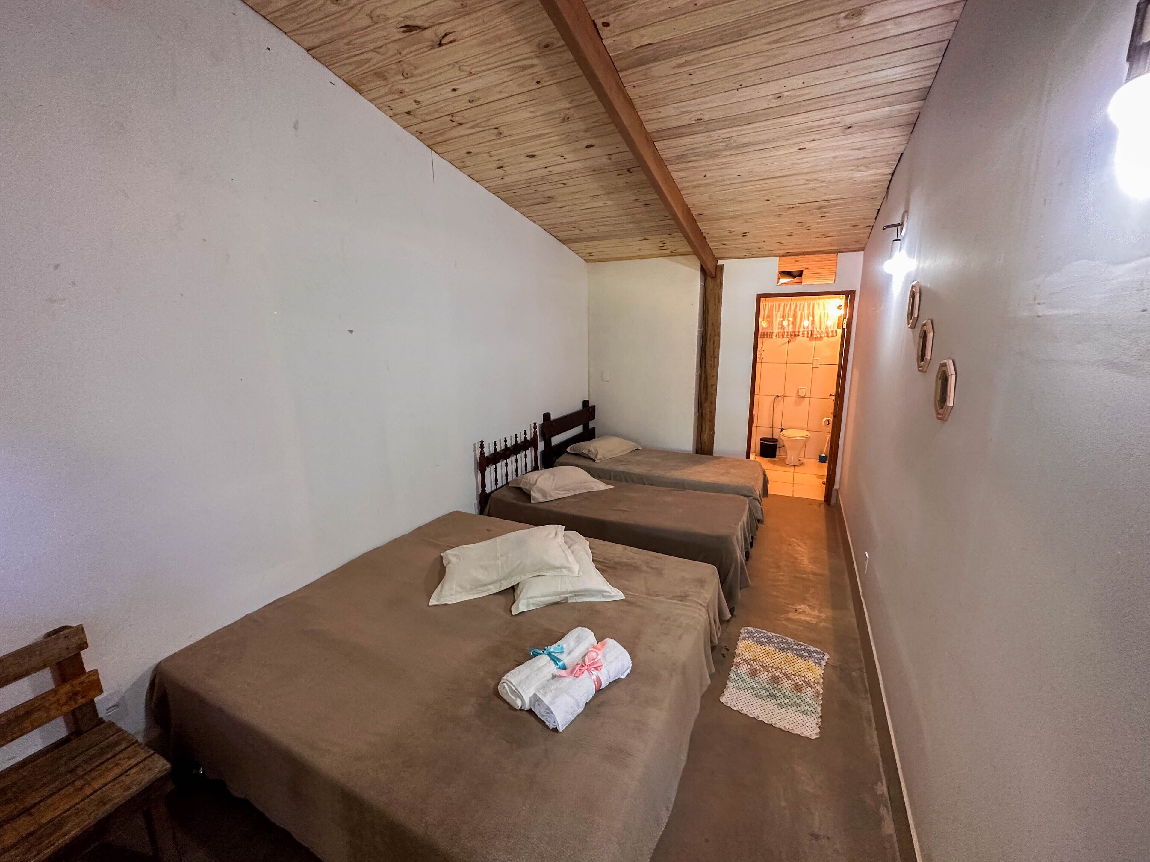 A room with two single beds, a wooden bench, and a small door leading to a bathroom.