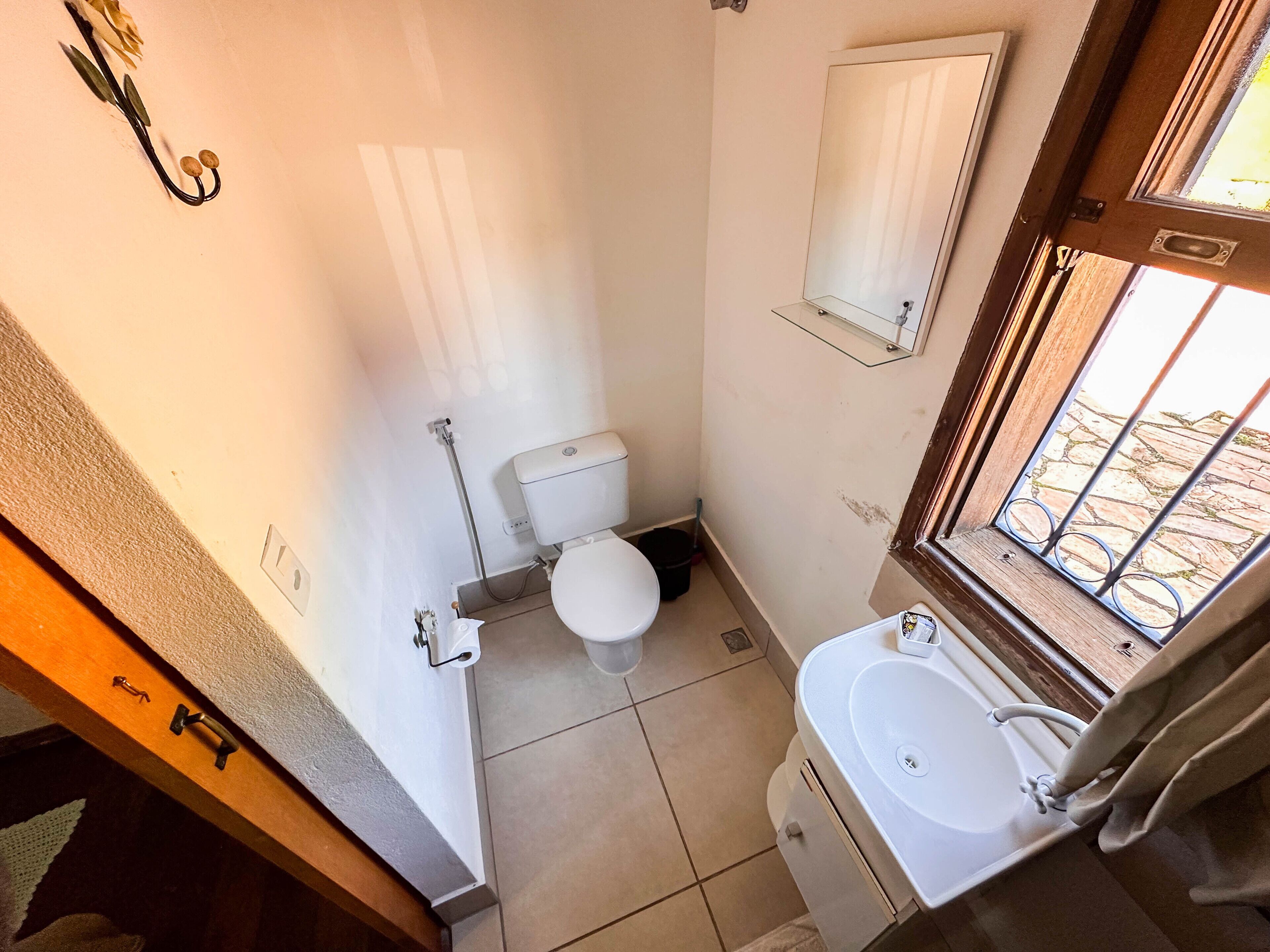 Ein kleines, kompaktes Badezimmer mit Toilette, Waschbecken und Spiegel.
