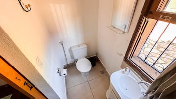 Ein kleines, kompaktes Badezimmer mit Toilette, Waschbecken und Spiegel.