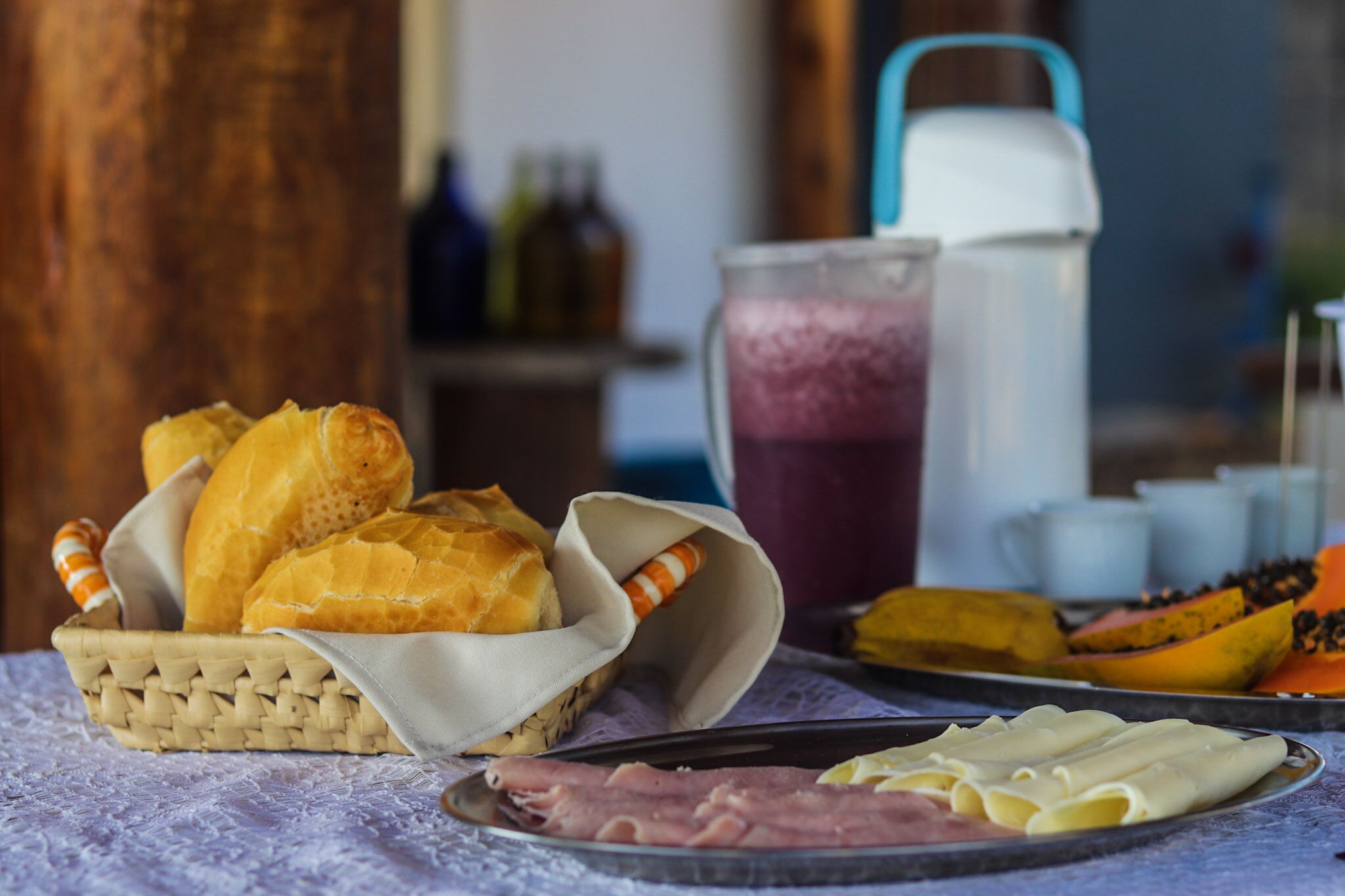 A breakfast setting with bread, ham, cheese, and fruit on a table.