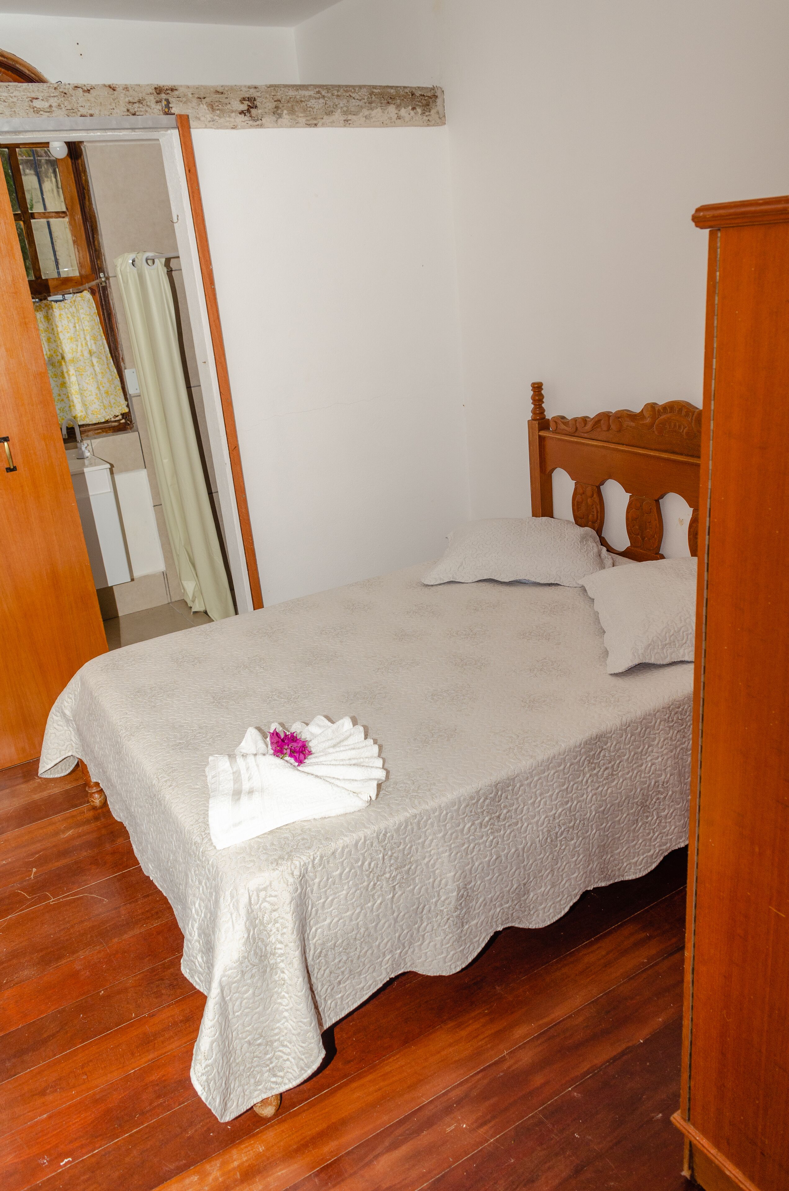 Ein ordentlich gemachtes Bett mit weißer Bettdecke, zwei Kissen und einem gefalteten Handtuch.