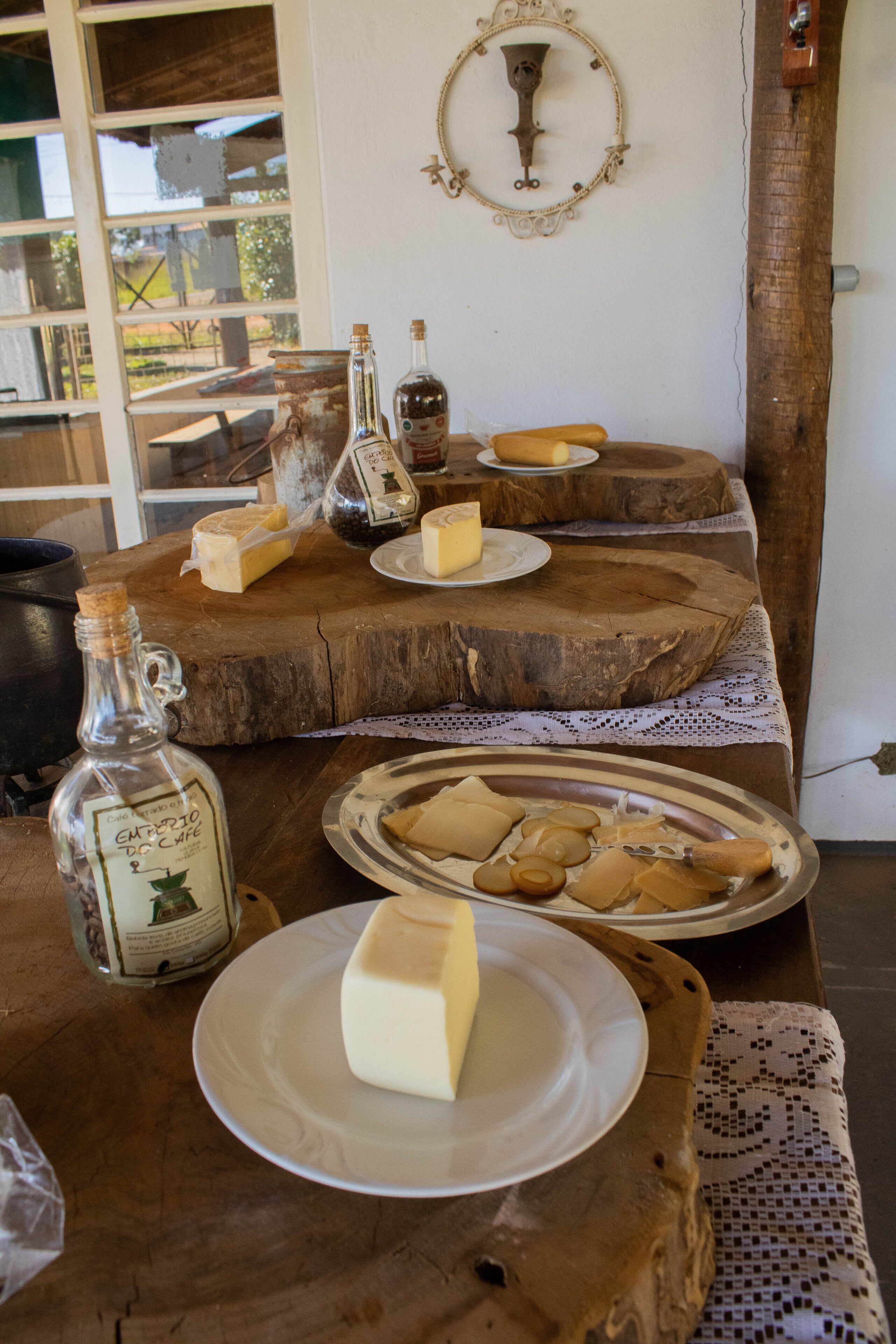 Una mesa de madera con queso, botellas y una vela.