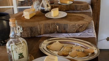 Una mesa de madera con queso, botellas y una vela.