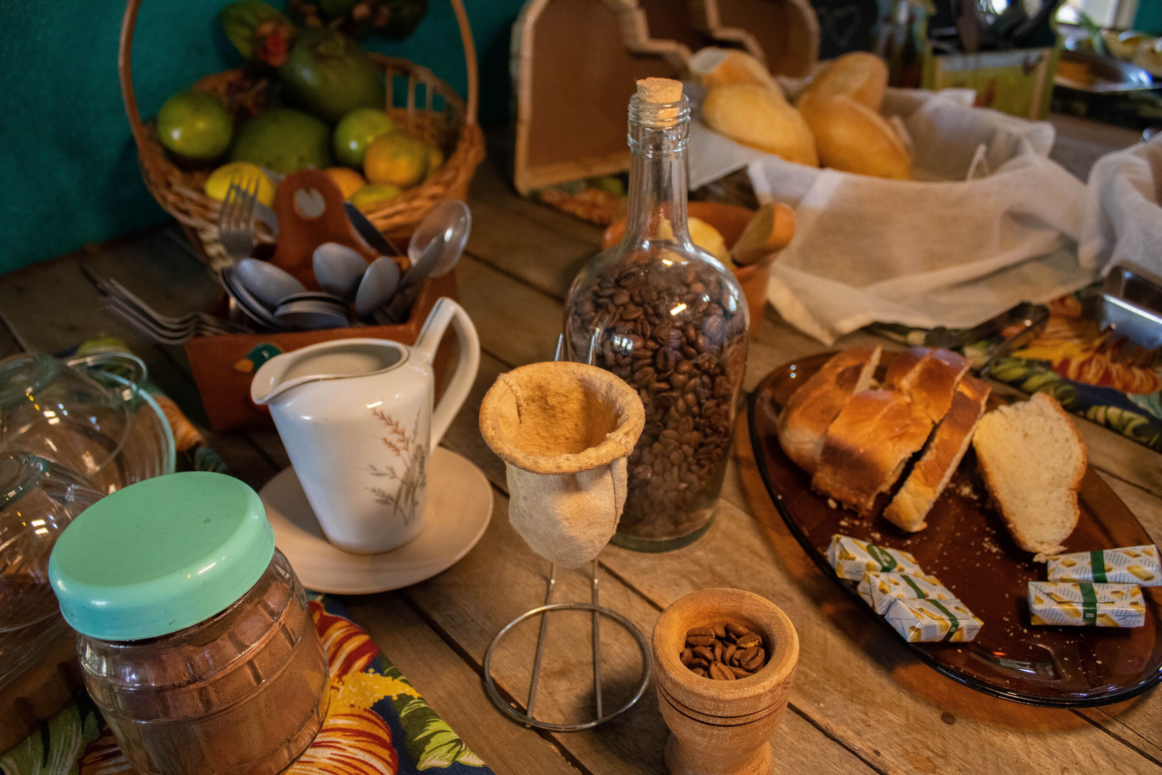 A wooden table with various food items, including bread, coffee beans, and condiments.