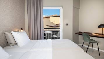 Une chambre d’hôtel avec un lit, un bureau, une chaise et une vue sur un balcon.