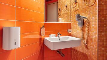 A bathroom with orange tiles, a white sink, a mirror, and a towel rack.