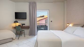 Habitación de hotel con una cama, un escritorio con silla, televisión y vistas a edificios.