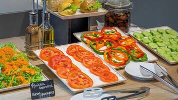 A buffet table with fresh vegetables, sandwiches, and condiments.