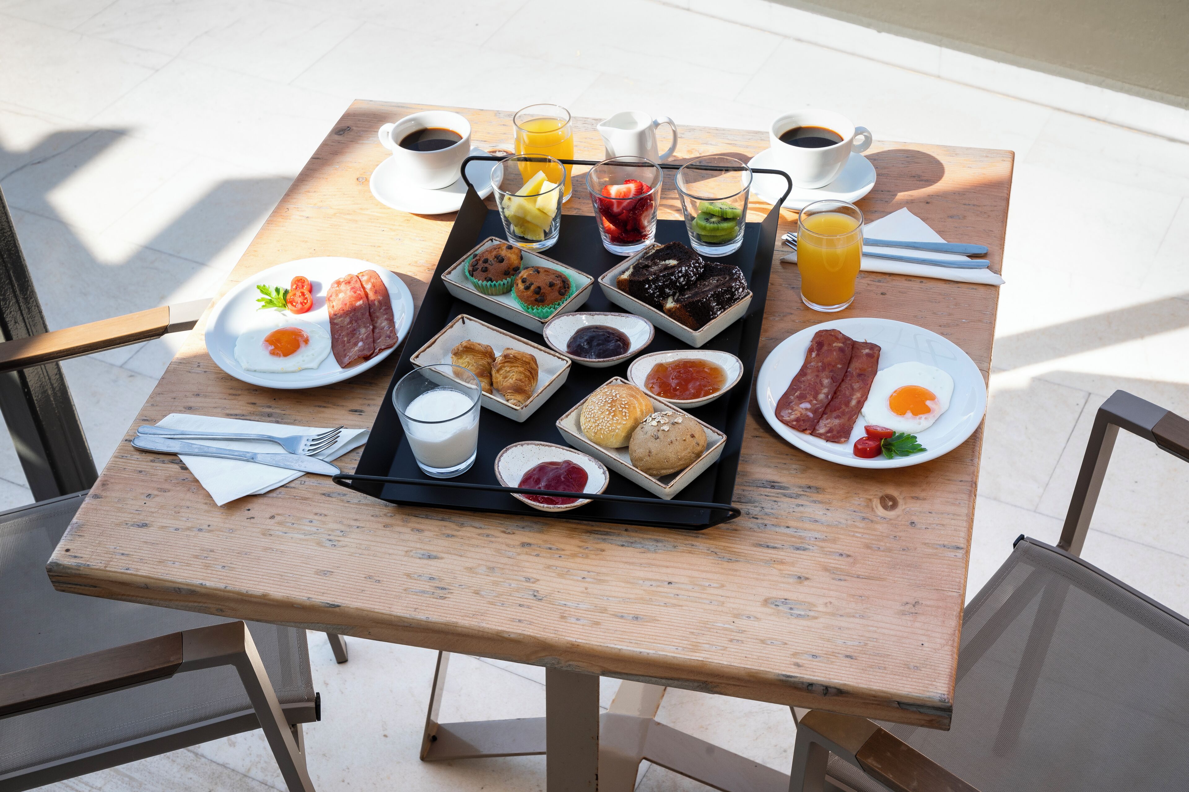 A breakfast tray with various foods and drinks on a wooden table.