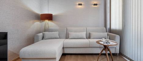 A modern living room with a sectional sofa, a small wooden side table, and a floor lamp.