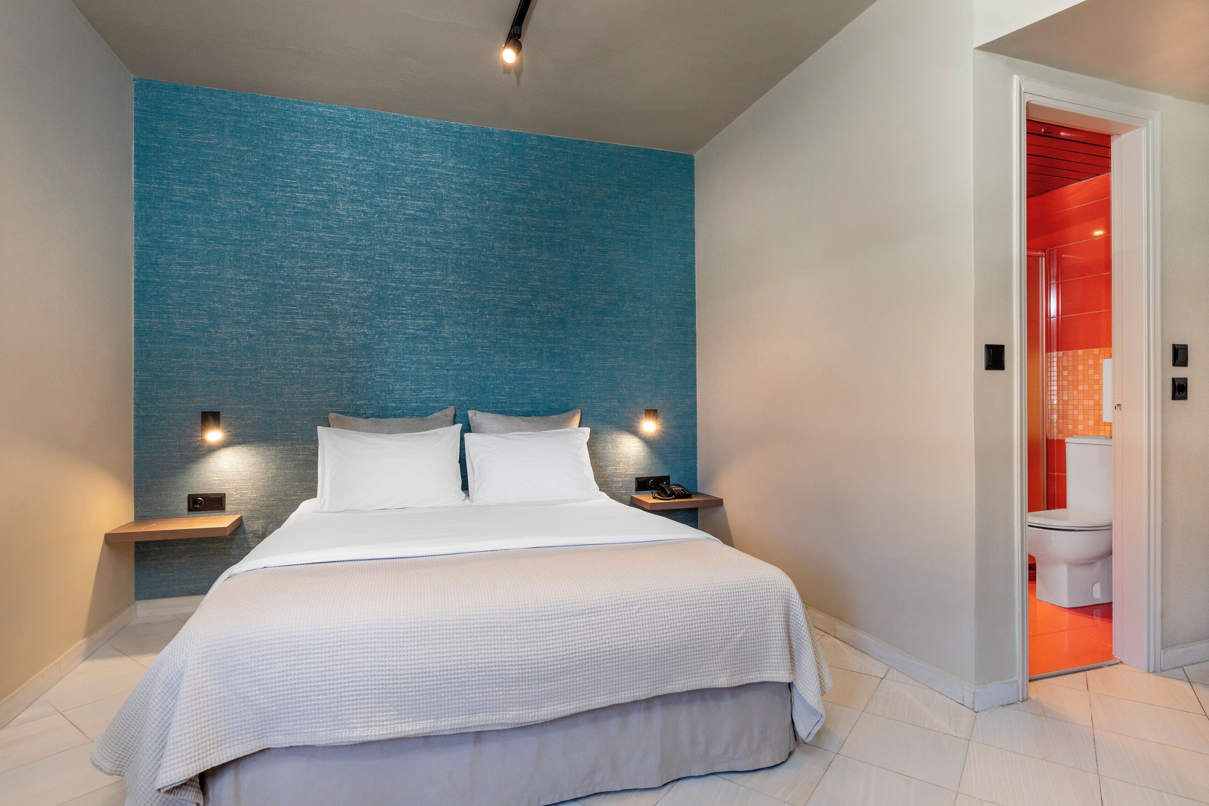 Et moderne hotelværelse med en stor seng, to sengeborde med lamper og udsigt til badeværelset.