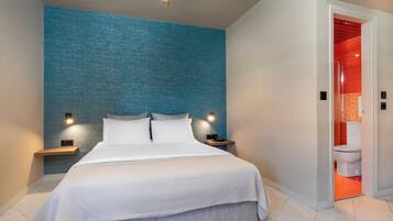 Et moderne hotelværelse med en stor seng, to sengeborde med lamper og udsigt til badeværelset.