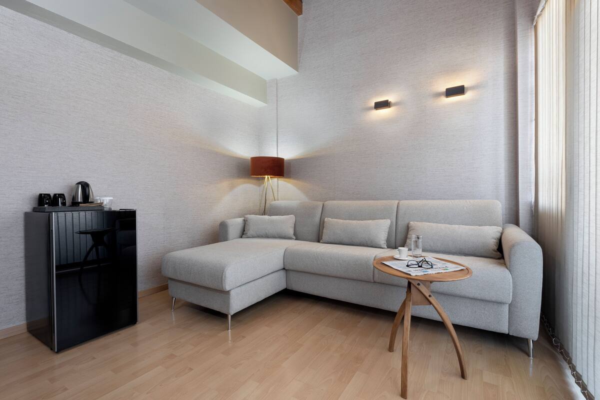 A modern living room with a sectional sofa, a small wooden table, and a black cabinet.