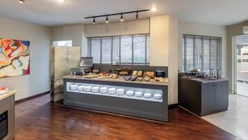 A modern kitchen with a buffet counter displaying various food items and a selection of plates.