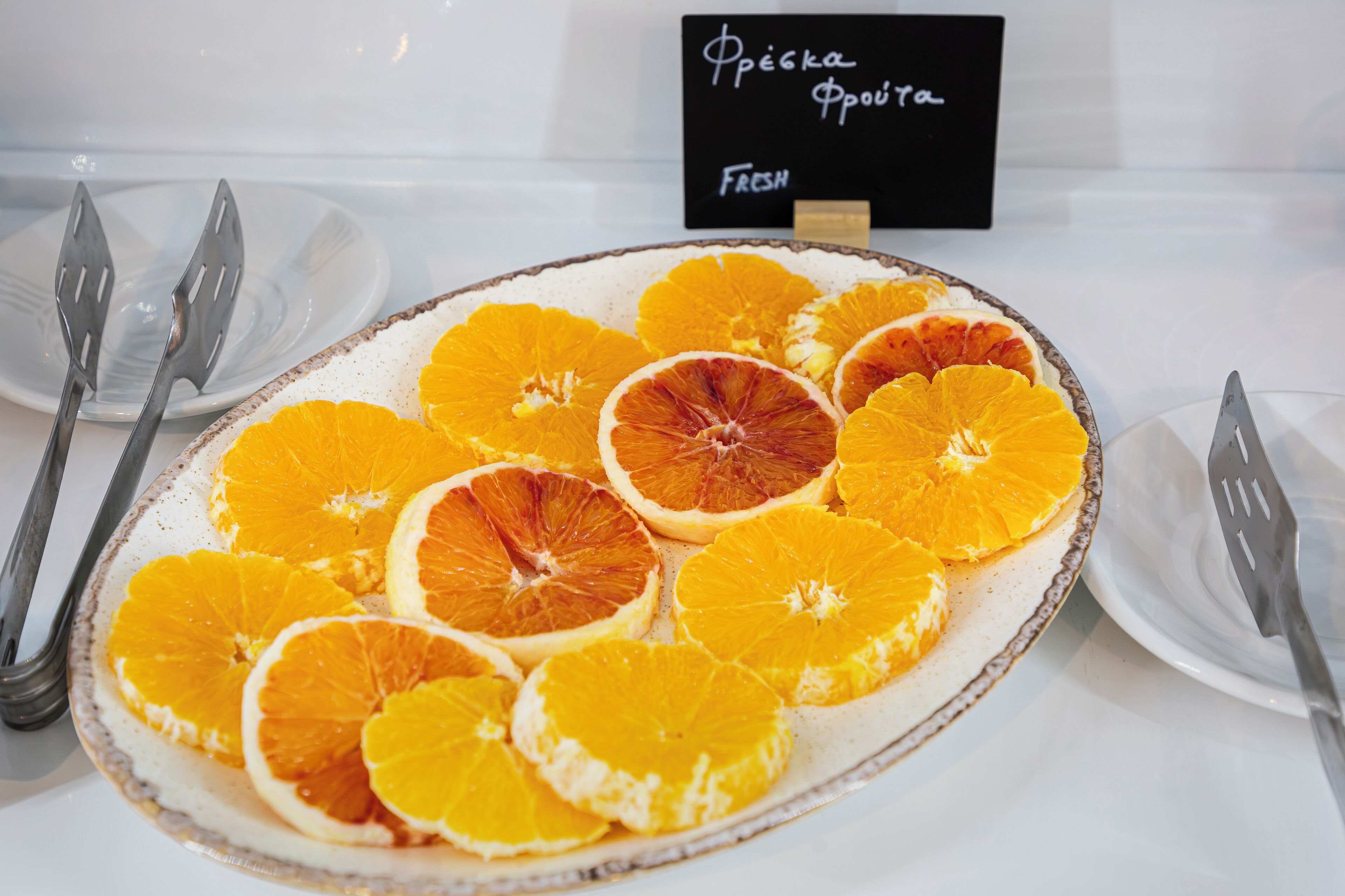A plate of sliced oranges with a sign in the background.