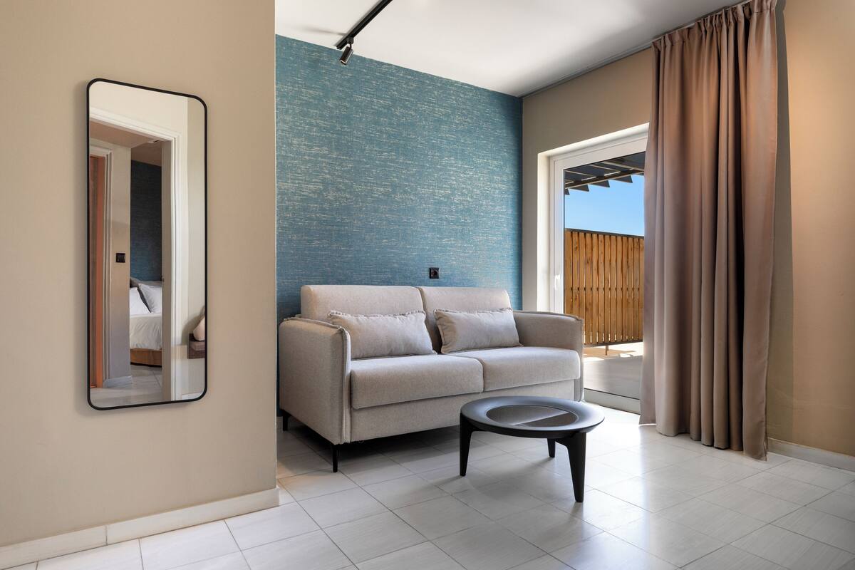 A living room with a sofa, a coffee table, and a mirror on the wall.