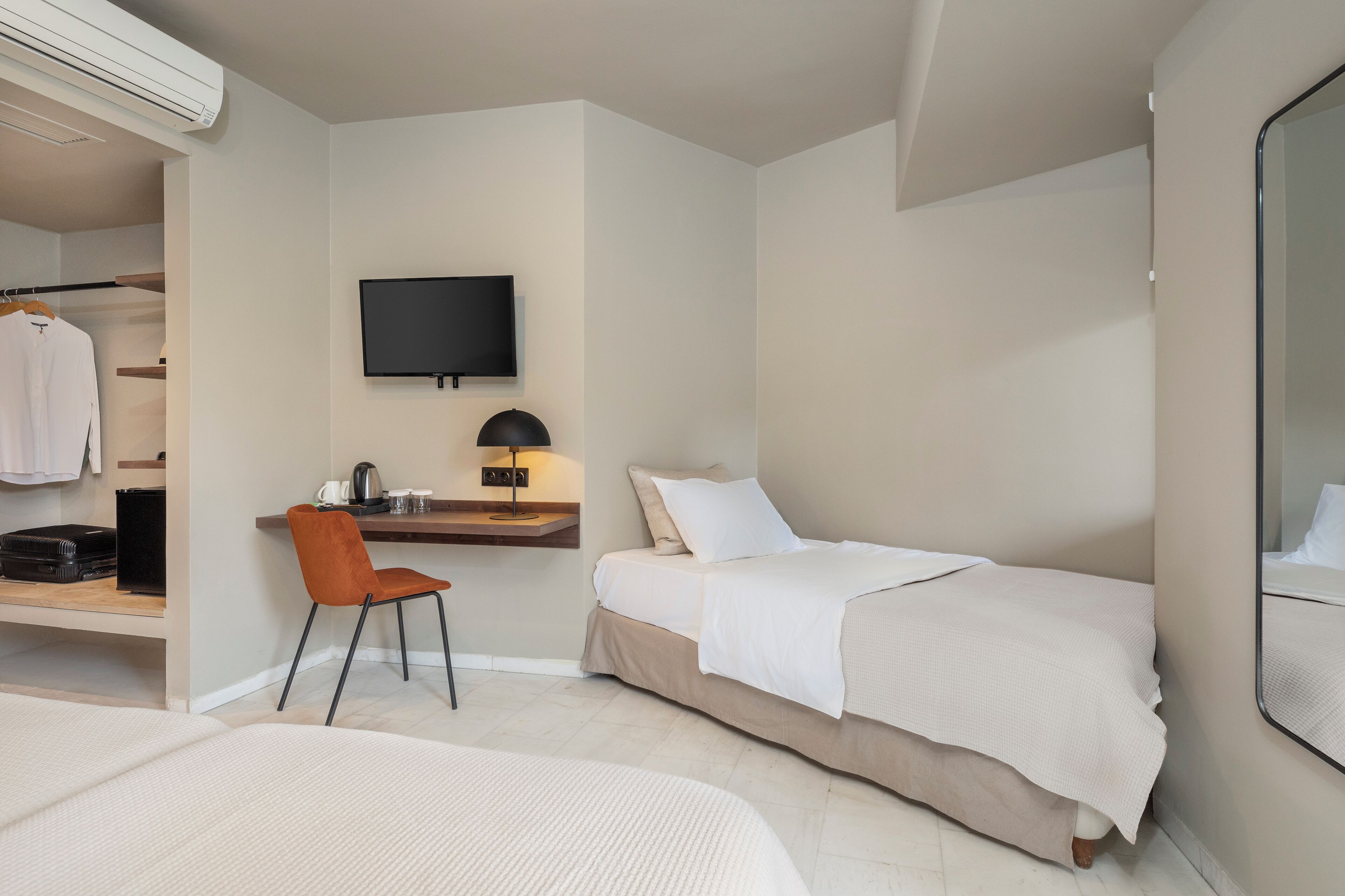 Een hotelkamer met een bed, een bureau met stoel, een televisie en een kledingkast.
