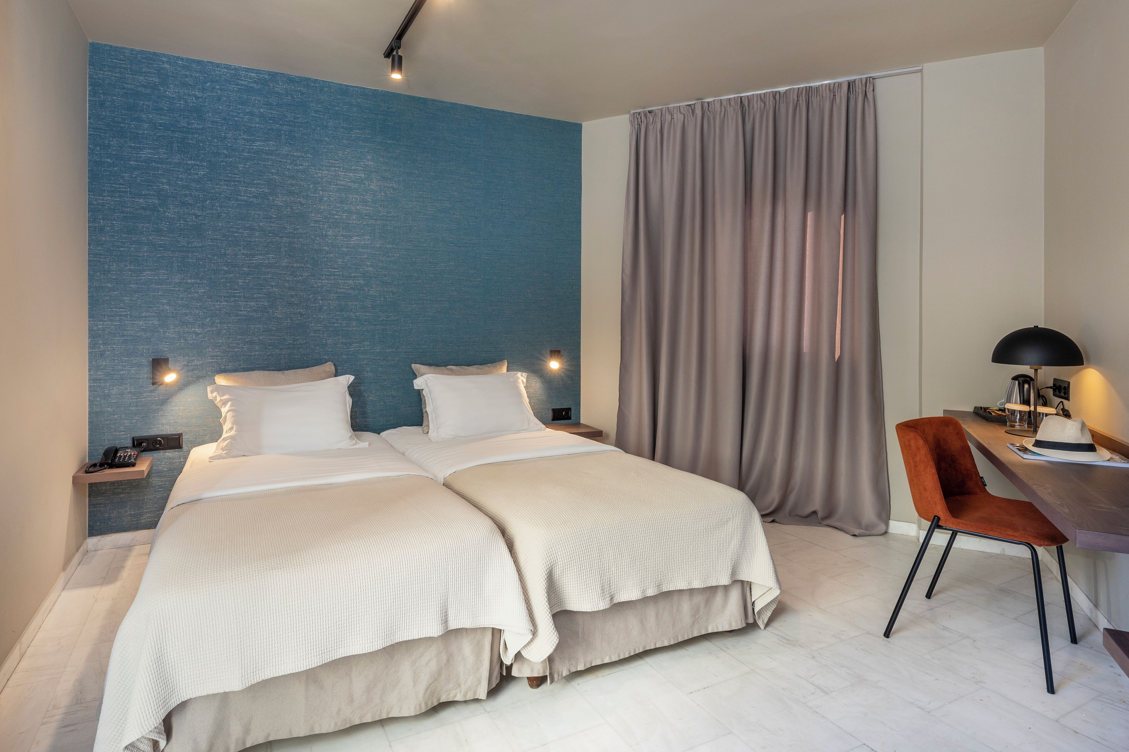 A hotel room with a large bed, a desk with a chair, and a view of the city.
