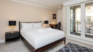 A neatly made bed with white linens, a dark wooden headboard, and two bedside tables with lamps. - At Home in Marylebone (London)
