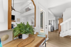 A spacious living area with a wooden floor, a large plant, and a bookshelf. - Renovated on the Lagoon within Walking Distance to the Beach &
Amenity Cards! (Seabrook Island)