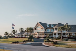 A large, multi-story residential building with a curved roof, multiple balconies, and a well-maintained lawn.