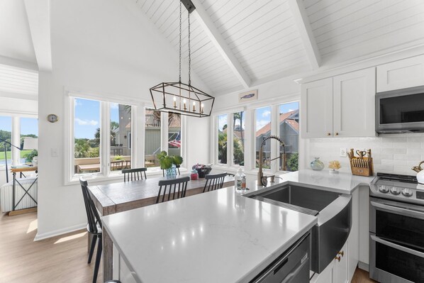 A spacious kitchen with a large island, white cabinetry, and a modern pendant light. - Renovated on the Lagoon within Walking Distance to the Beach &
Amenity Cards! (Seabrook Island)