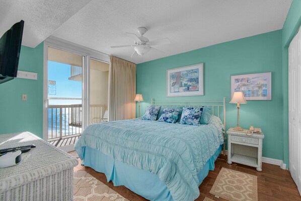 Une chambre à coucher comprenant un lit, une table de chevet, une chaise, un ventilateur de plafond et un balcon avec vue.