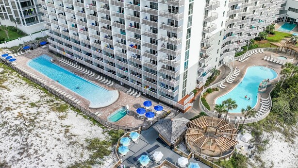 Ett högt hotell med flera balkonger, en central pool och ett separat poolområde.