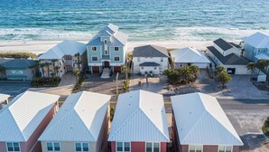 A coastal residential area with houses featuring gabled roofs and a beach in the background. - Steps to Beach-Ocean views with both lake & pool (Panama City Beach)