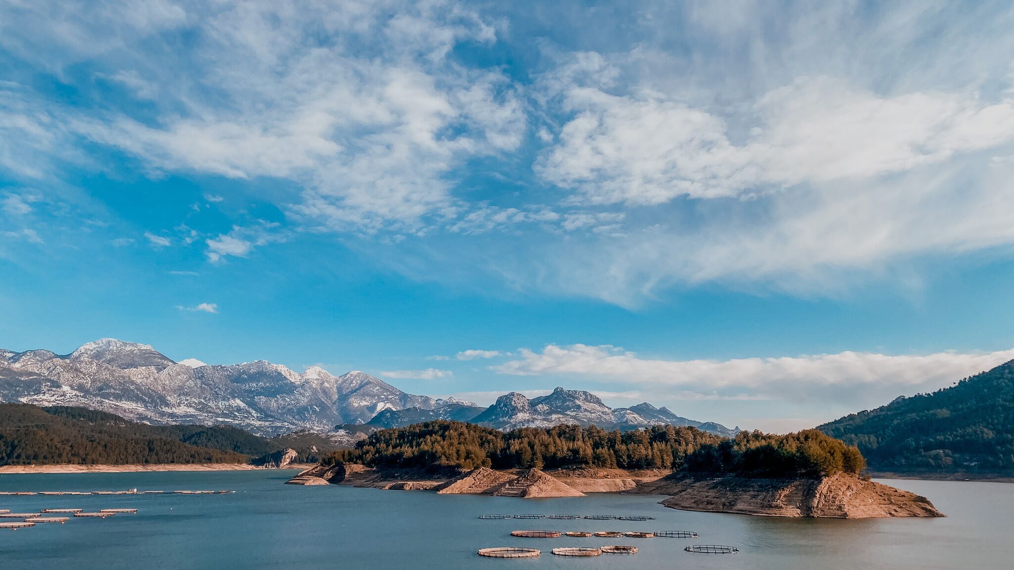 A lake with mountains in the background and a forested area in the middle.
