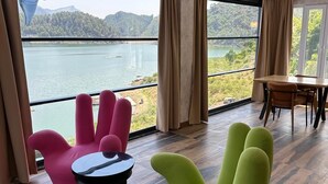 A modern room with large windows offering a lake view, a dining area, and colorful chairs. - Dolphin Boutique Hotel & Restaurant (Bucak)