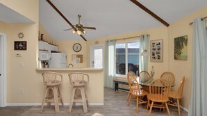 A kitchen with a ceiling fan, a dining area with wooden chairs, and a view of the outdoors through a window. - Marathon FL Waterfront Home | 30ft Dock (Marathon)