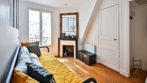 A bedroom with a bed, a fireplace, a large window, and a door.