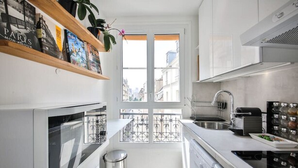 A modern kitchen with white cabinets, a stainless steel sink, and a built-in oven.