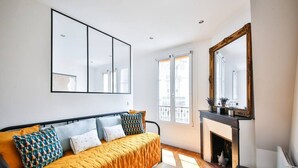 A modern bedroom with a bed, a fireplace, and large windows.