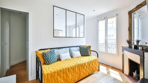 A modern bedroom with a bed, a fireplace, and large windows.