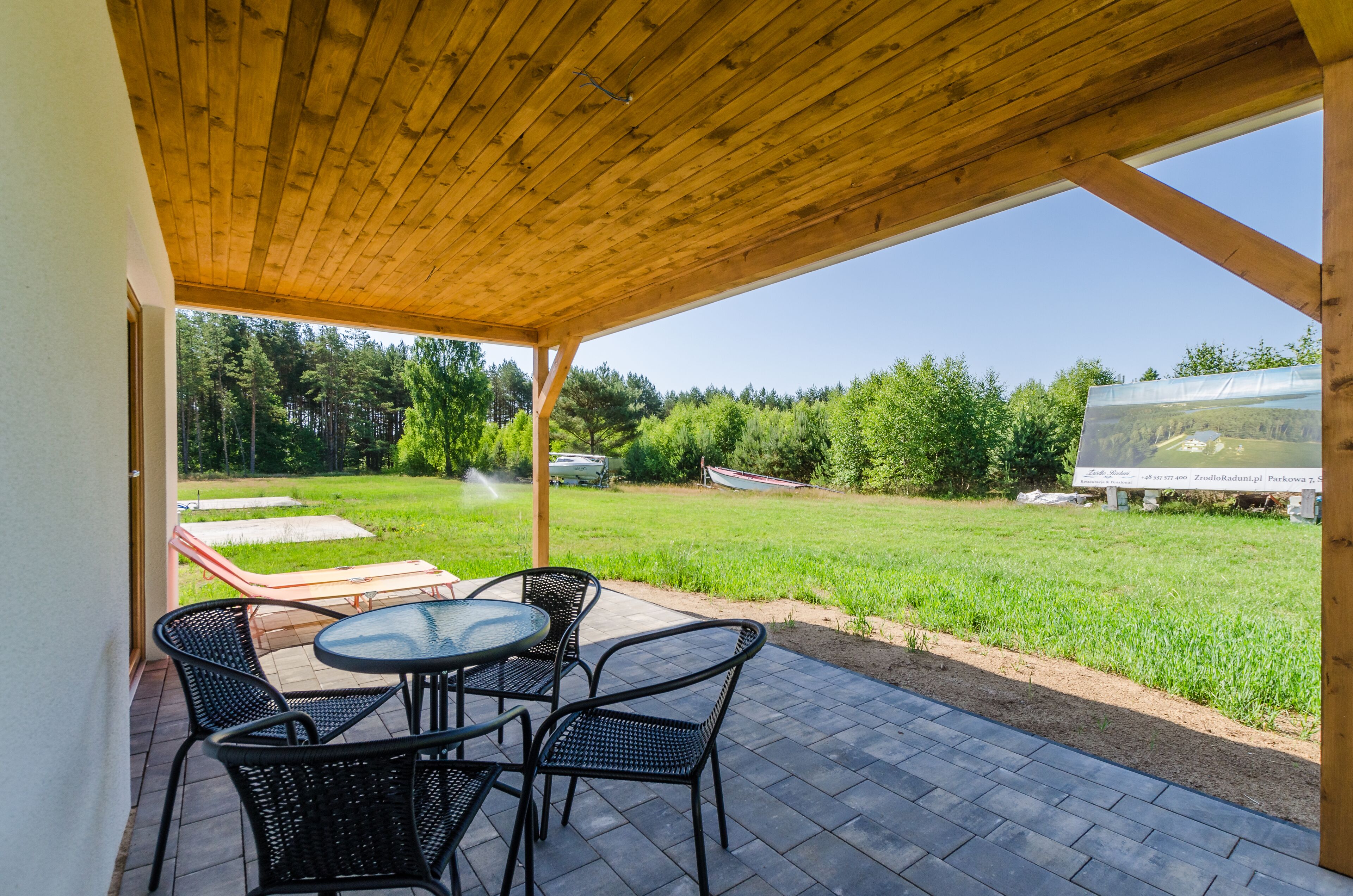 An outdoor patio with a wooden ceiling, a round table, and four chairs.