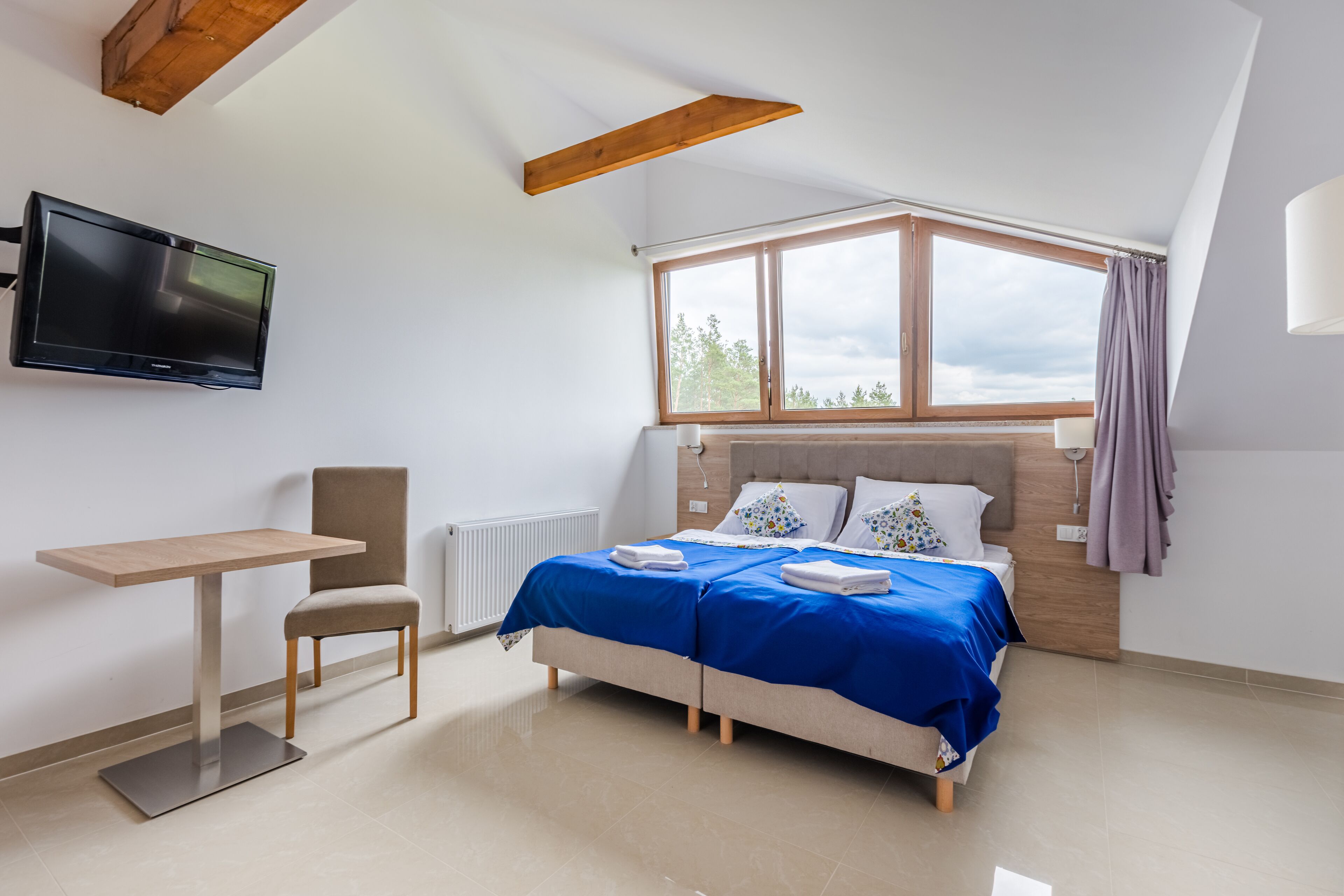 Un dormitorio moderno con cama, escritorio y televisor.