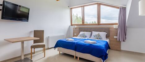 A modern bedroom with a bed, a desk, and a TV.